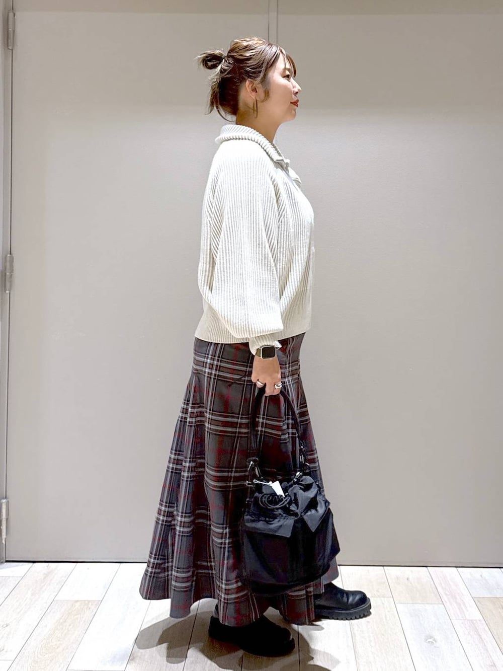 ブラック系のショルダーバッグ、ホワイト系のカーディガン/ボレロ、ブラック系のブーツを着用したレディースの冬コーディネートの2枚目の写真