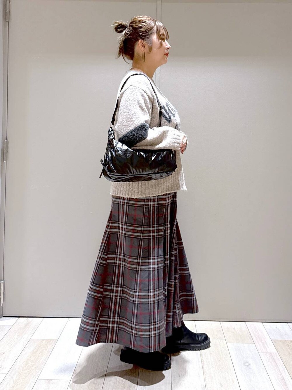 グレー系のスカート、ブラック系のブーツ、ブラック系のショルダーバッグを着用したレディースの冬コーディネートの2枚目の写真