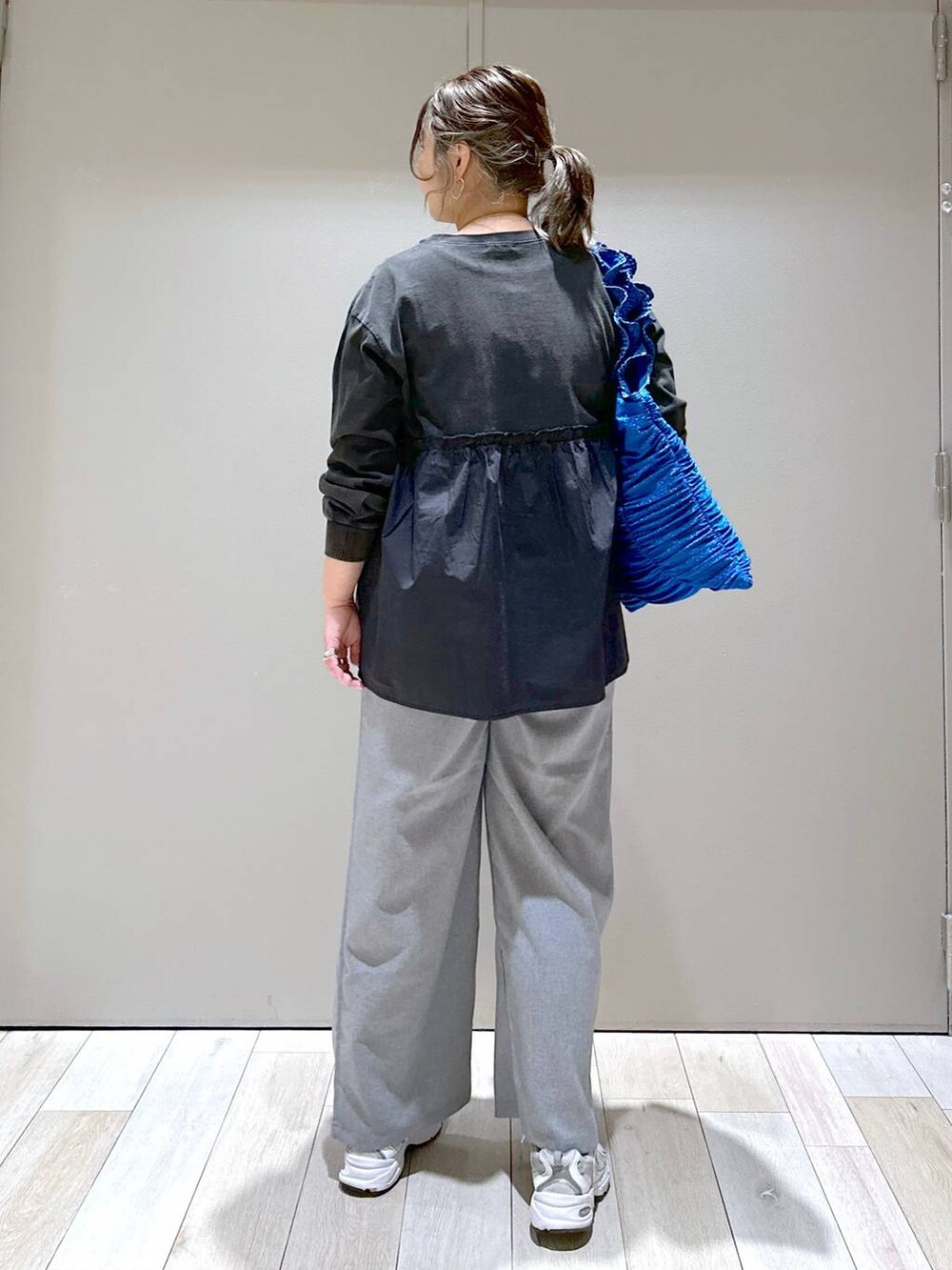 ブルー系のトートバッグ、グレー系のスラックス、グレー系のTシャツ/カットソーを着用したレディースの冬コーディネートの3枚目の写真