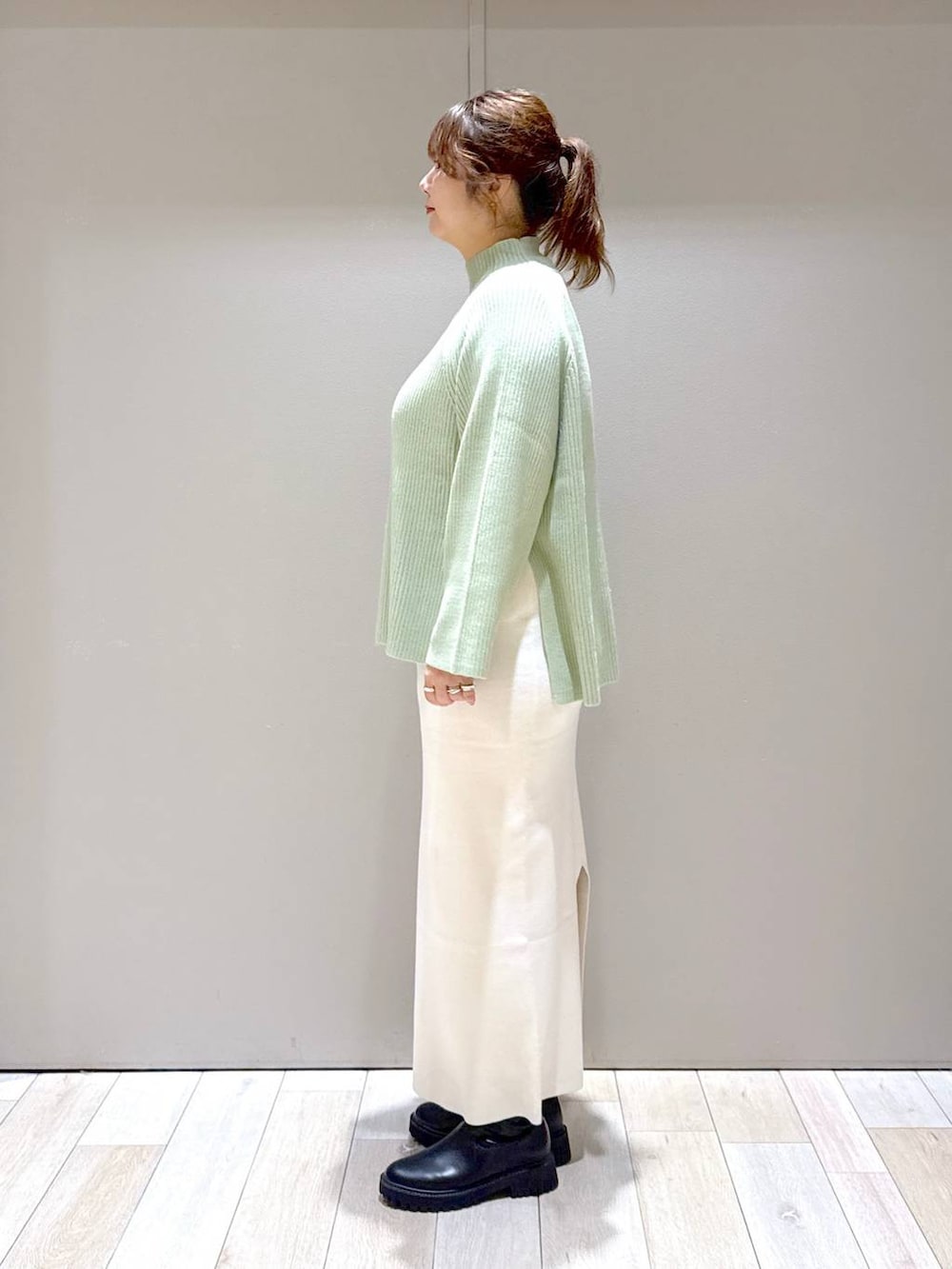 ブラック系のスカート、ブラック系のブーツ、ホワイト系のニット/セーターを着用したレディースの冬コーディネートの4枚目の写真