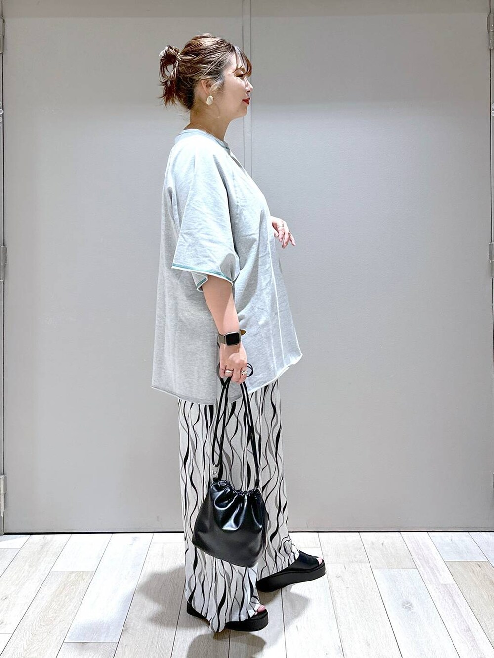ブラック系のショルダーバッグ、グレー系のTシャツ/カットソー、ブラック系のサンダルを着用したレディースの春コーディネートの2枚目の写真