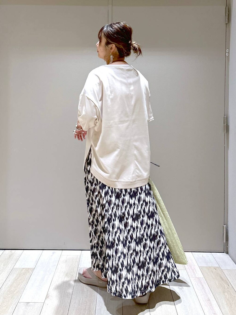 ゴールド系のショルダーバッグ、ブラック系のスカート、ベージュ系のTシャツ/カットソーを着用したレディースの春コーディネートの3枚目の写真