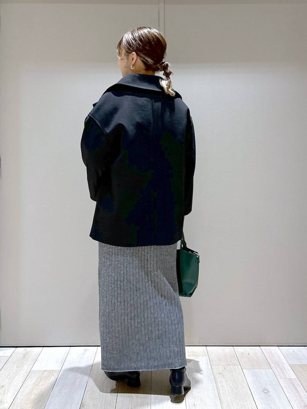 グリーン系のショルダーバッグ、ブラック系のピーコート、ブラック系のブーツを着用したレディースの秋コーディネートの3枚目の写真