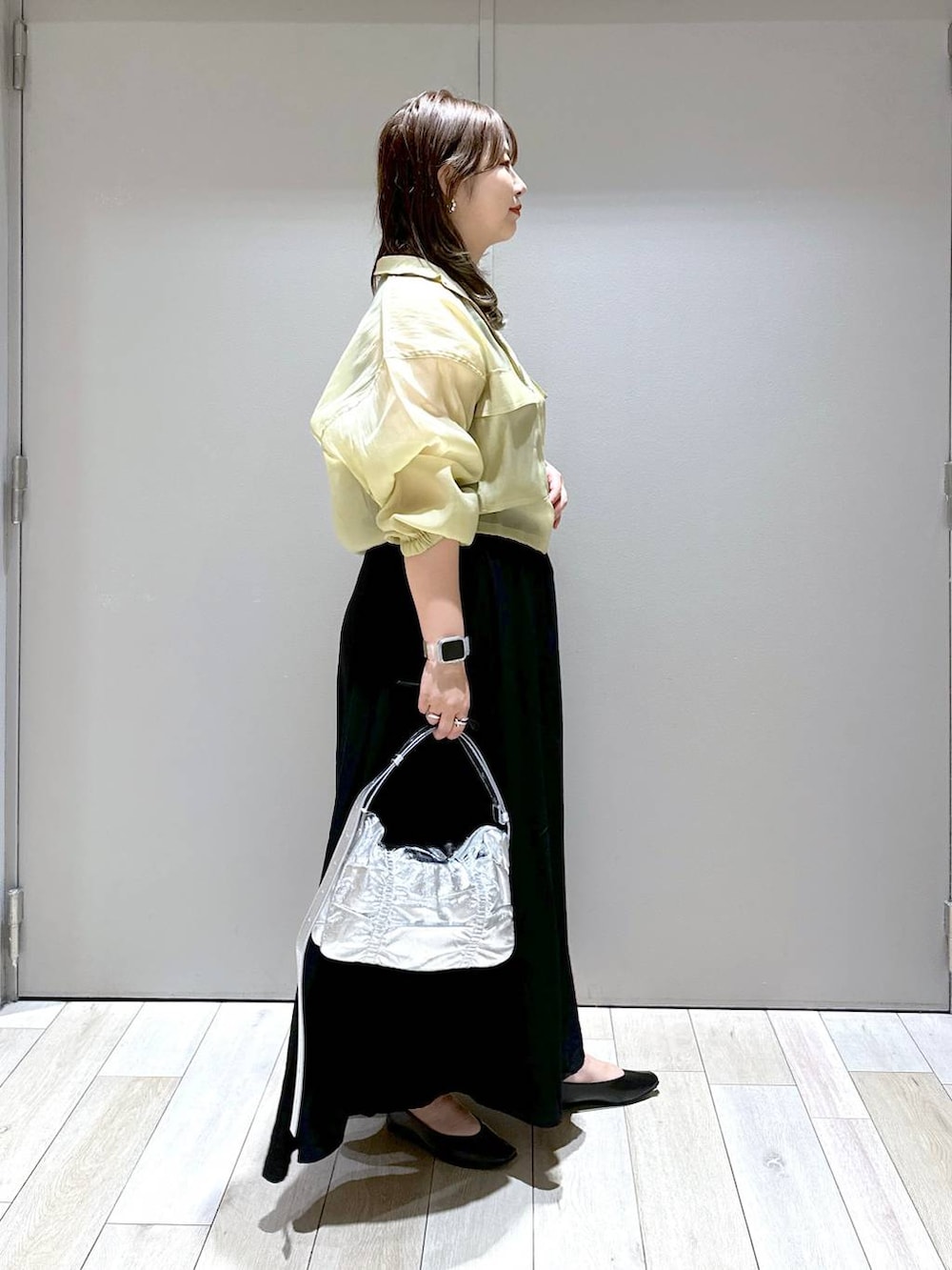 シルバー系のショルダーバッグ、ブラック系のパンプス、ブラック系のスカートを着用したレディースの秋コーディネートの2枚目の写真
