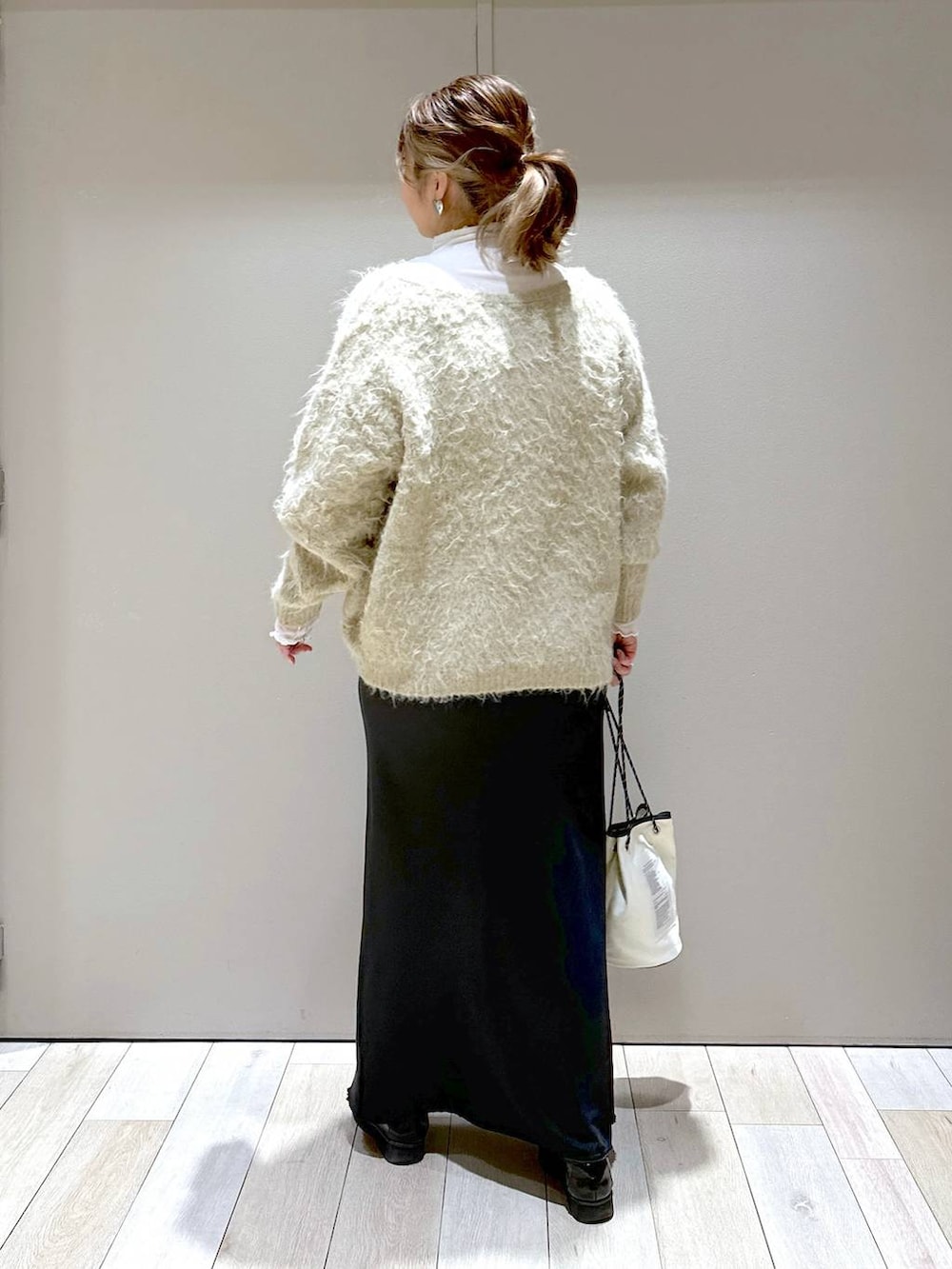 ホワイト系のTシャツ/カットソー、ブラック系のブーツ、ブラック系のスカートを着用したレディースの冬コーディネートの4枚目の写真