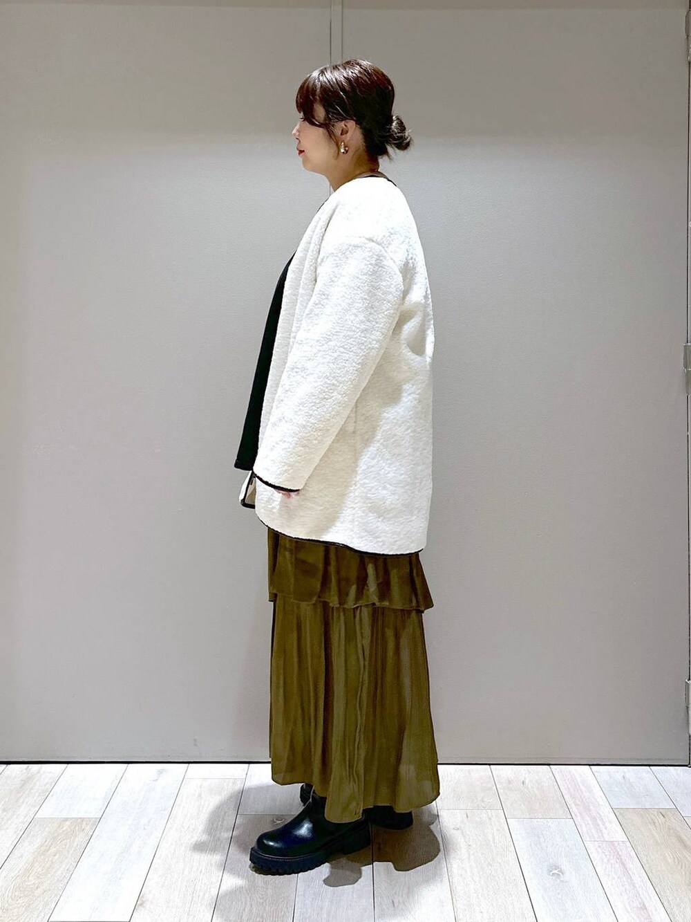 ホワイト系のボストンバッグ、ホワイト系のその他アウター、ブラック系のブーツを着用したレディースの秋コーディネートの4枚目の写真