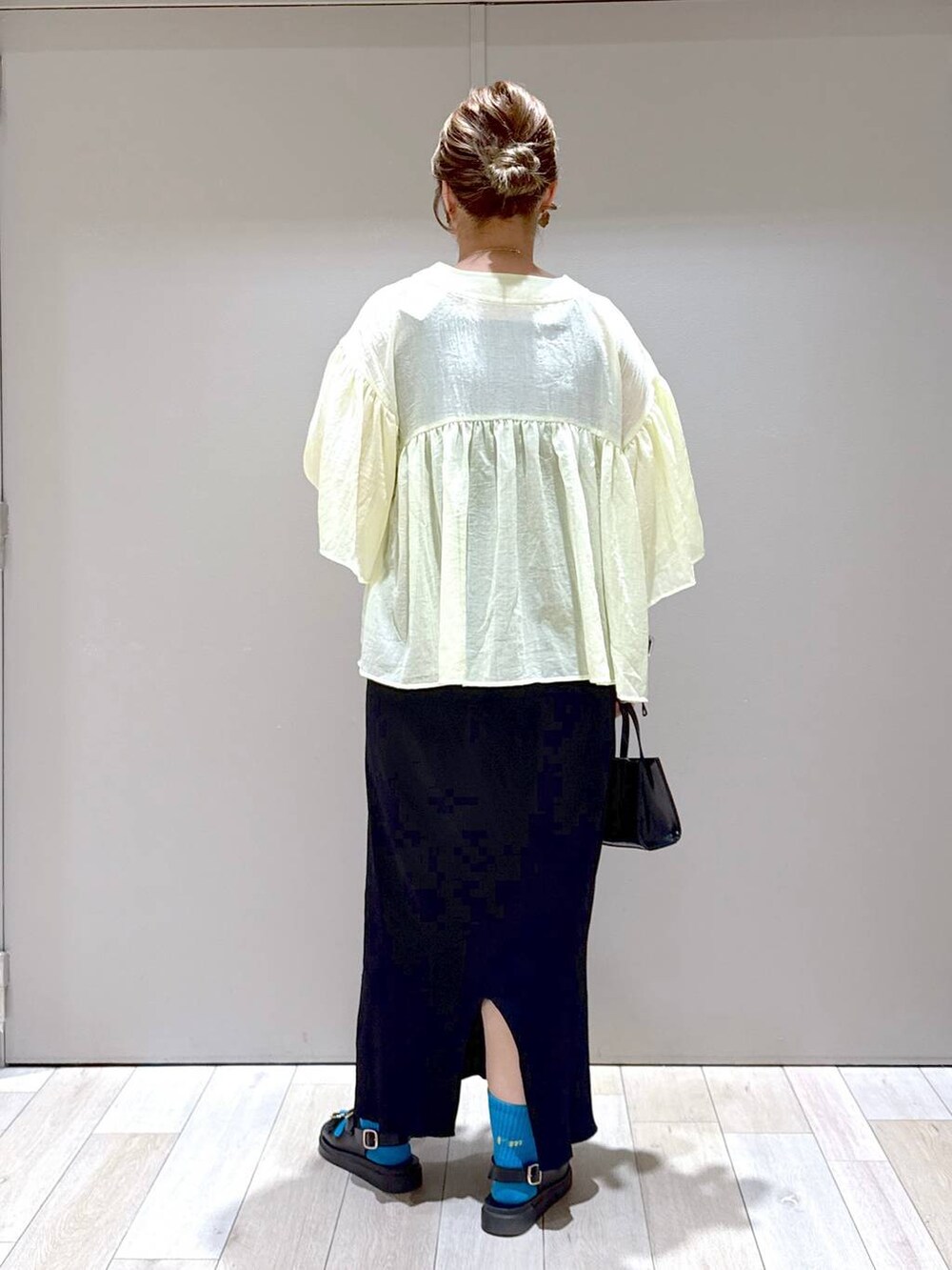 ブラック系のスカート、イエロー系のシャツ/ブラウス、ブラック系のサンダルを着用したレディースの夏コーディネートの3枚目の写真