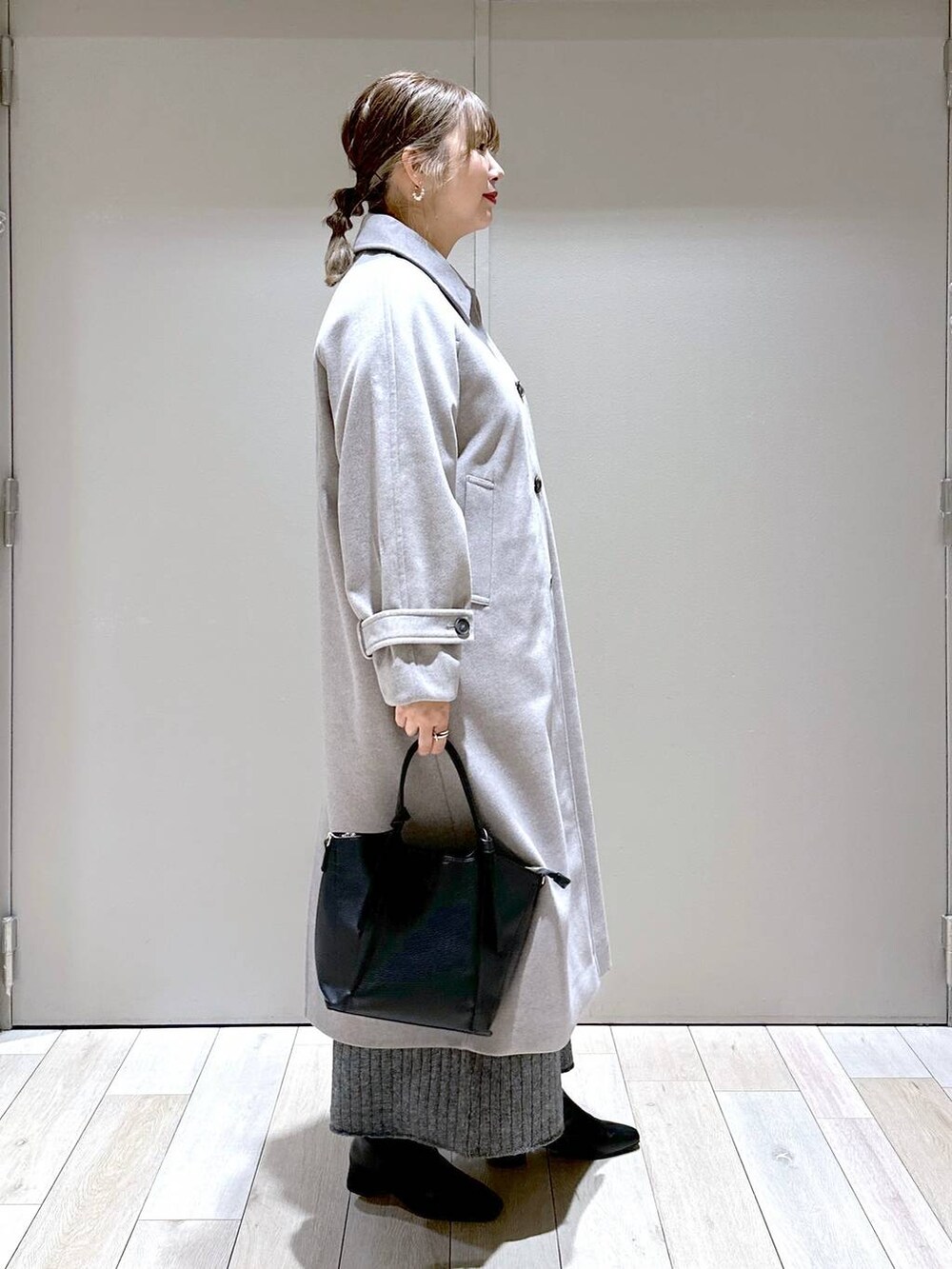 ブラック系のショルダーバッグ、グレー系のステンカラーコート、ブラック系のブーツを着用したレディースの秋コーディネートの2枚目の写真