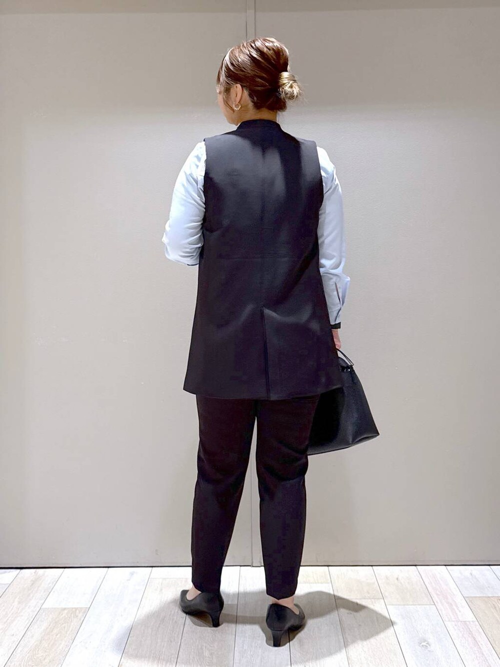 ブラック系のスーツパンツ、ブラック系のスーツベスト、ブルー系のシャツ/ブラウスを着用したレディースの冬コーディネートの3枚目の写真