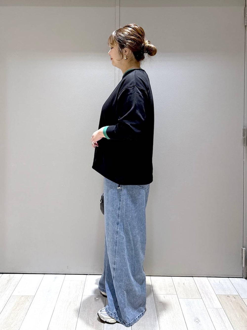 ブラック系のショルダーバッグ、ブラック系のTシャツ/カットソー、ブルー系のデニムパンツを着用したレディースの秋コーディネートの4枚目の写真