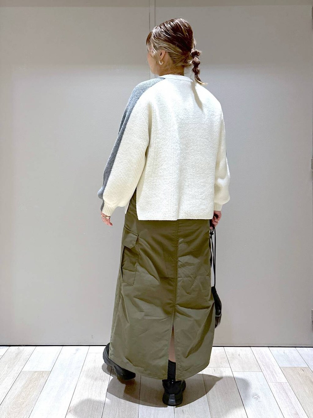 ホワイト系のニット/セーター、グリーン系のスカート、ブラック系のブーツを着用したレディースの冬コーディネートの5枚目の写真