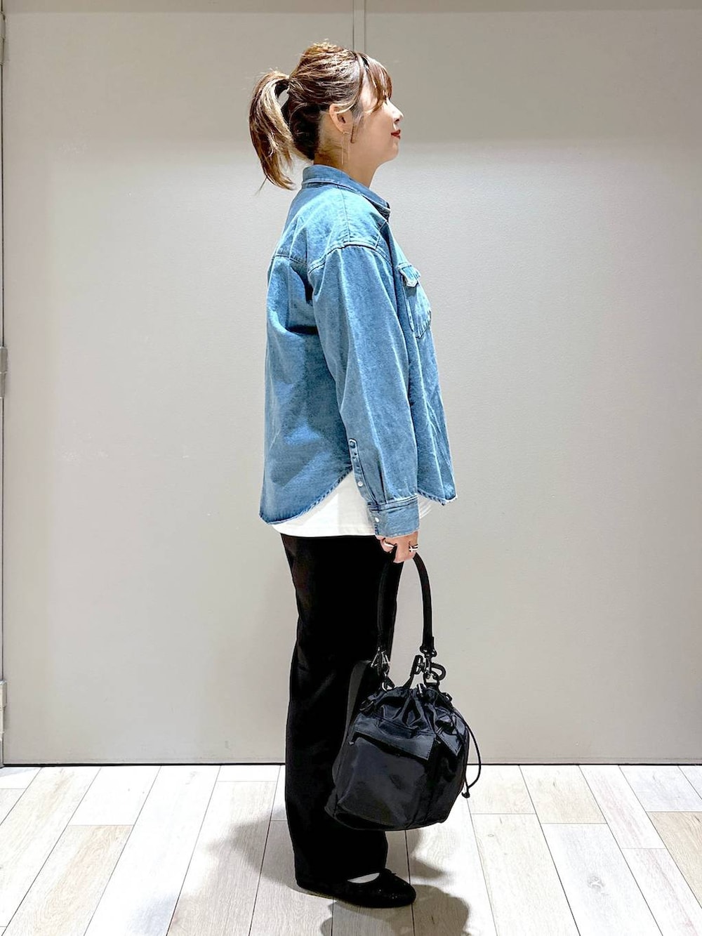 ブラック系のショルダーバッグ、ブラック系のバレエシューズ、ブルー系のシャツ/ブラウスを着用したレディースの秋コーディネートの2枚目の写真