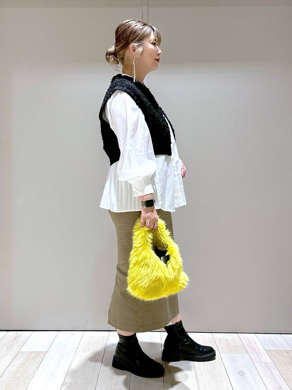 イエロー系のハンドバッグ、ブラック系のブーツ、ホワイト系のシャツ/ブラウスを着用したレディースの秋コーディネートの2枚目の写真