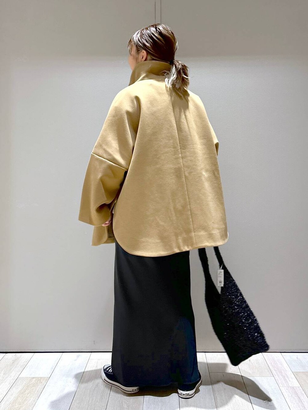 ブラウン系のポンチョ、ブラック系のショルダーバッグ、ブラック系のスカートを着用したレディースの秋コーディネートの3枚目の写真