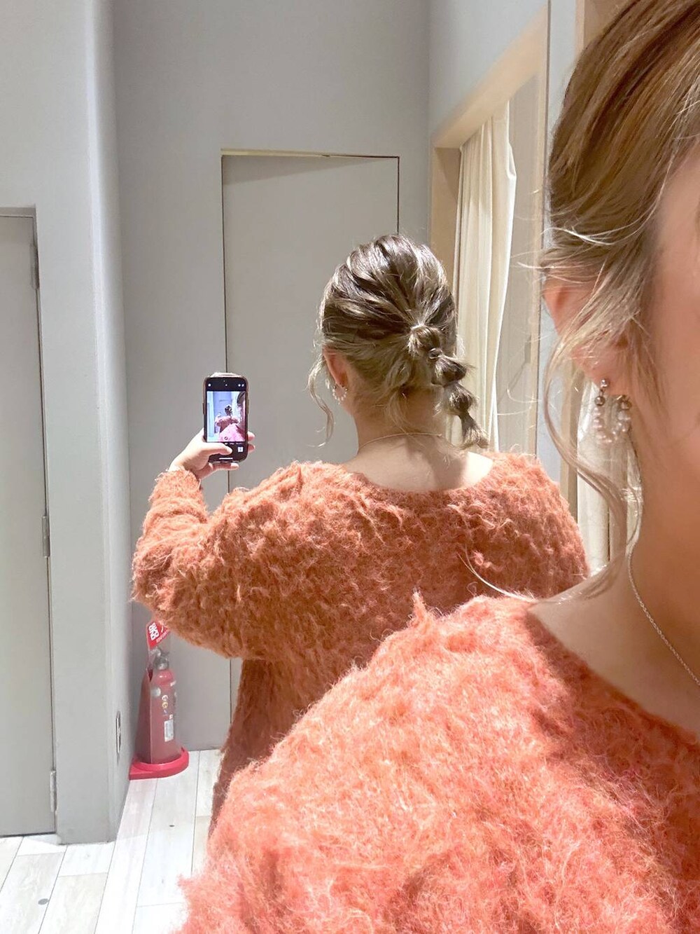 オレンジ系のカーディガン/ボレロ、グリーン系のスカート、ブラック系のブーツを着用したレディースの冬コーディネートの3枚目の写真