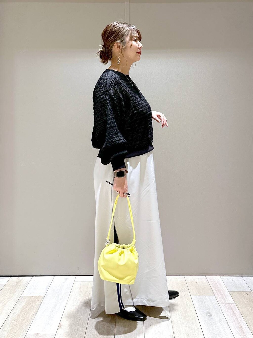 ブラック系のTシャツ/カットソー、ブラック系のパンプス、イエロー系のショルダーバッグを着用したレディースの春コーディネートの2枚目の写真