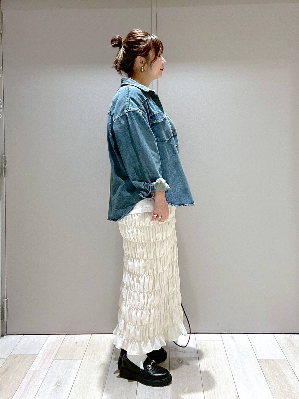 ホワイト系のスカート、ブラック系のローファー、ブラック系のショルダーバッグを着用したレディースの秋コーディネートの2枚目の写真