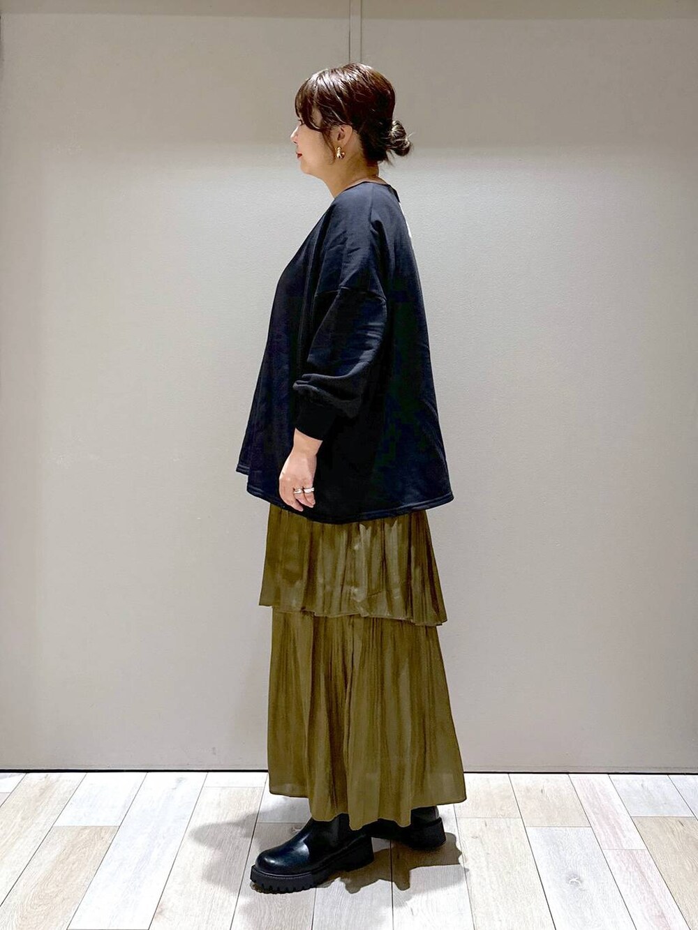 シルバー系のショルダーバッグ、ブラック系のブーツ、グリーン系のスカートを着用したレディースの秋コーディネートの4枚目の写真