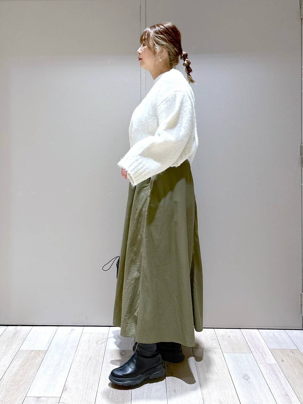 ブラック系のバックパック/リュック、ブラック系のブーツ、グリーン系のスカートを着用したレディースの冬コーディネートの2枚目の写真