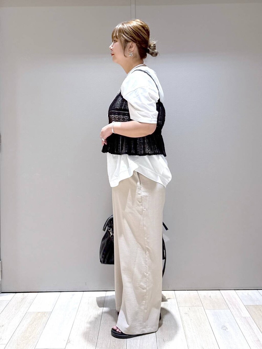 ブラック系のトートバッグ、ホワイト系のTシャツ/カットソー、ブラック系のサンダルを着用したレディースの春コーディネートの4枚目の写真