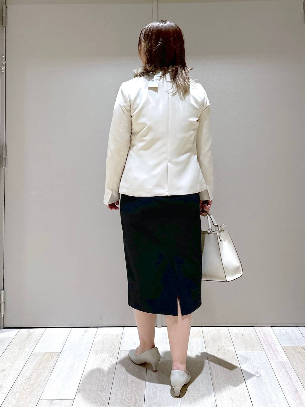 ブラック系のワンピース、ホワイト系のノーカラージャケット、ホワイト系のショルダーバッグを着用したレディースの春コーディネートの3枚目の写真