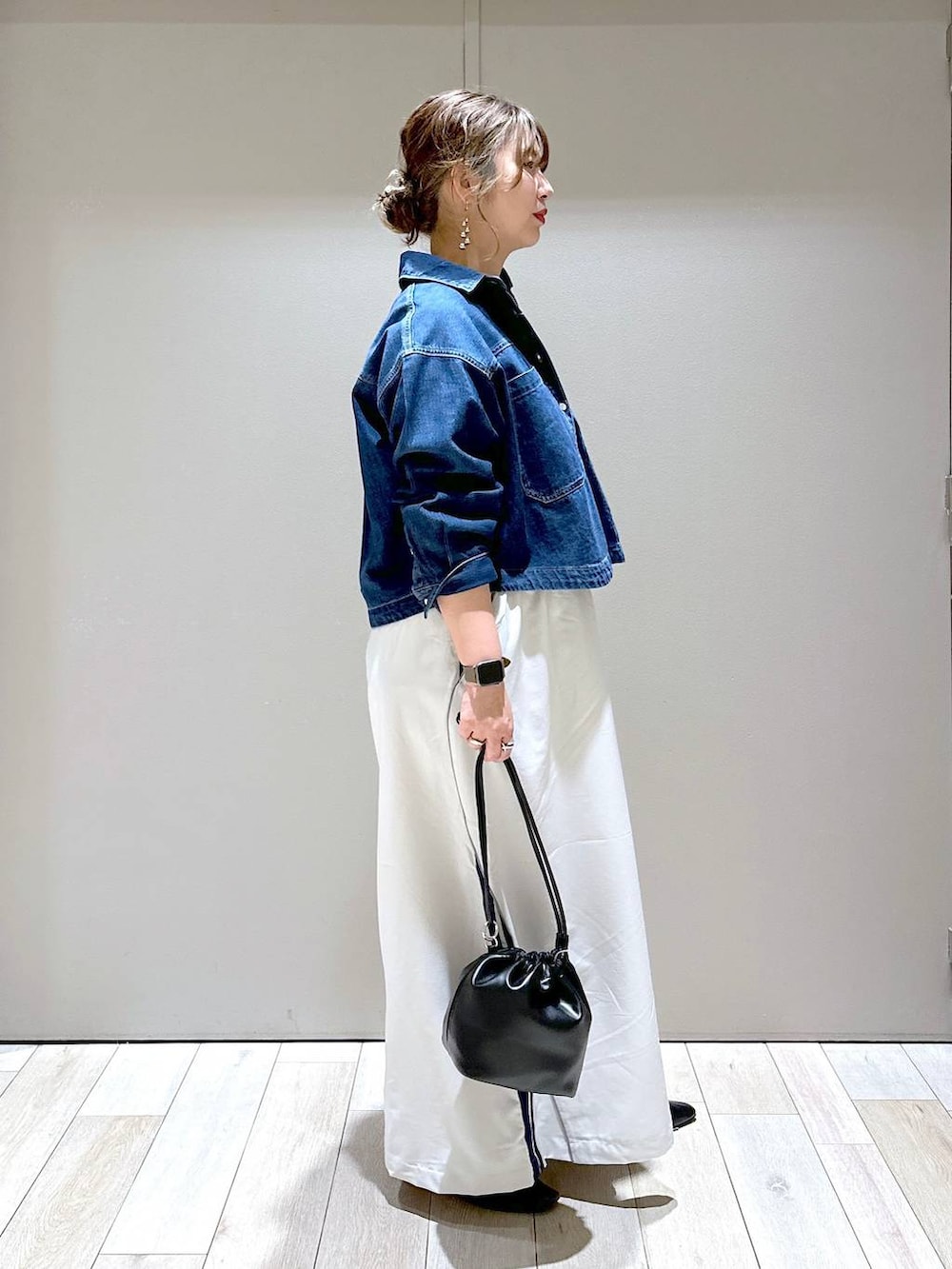 ブラック系のショルダーバッグ、ブラック系のパンプス、ブルー系のシャツ/ブラウスを着用したレディースの春コーディネートの2枚目の写真