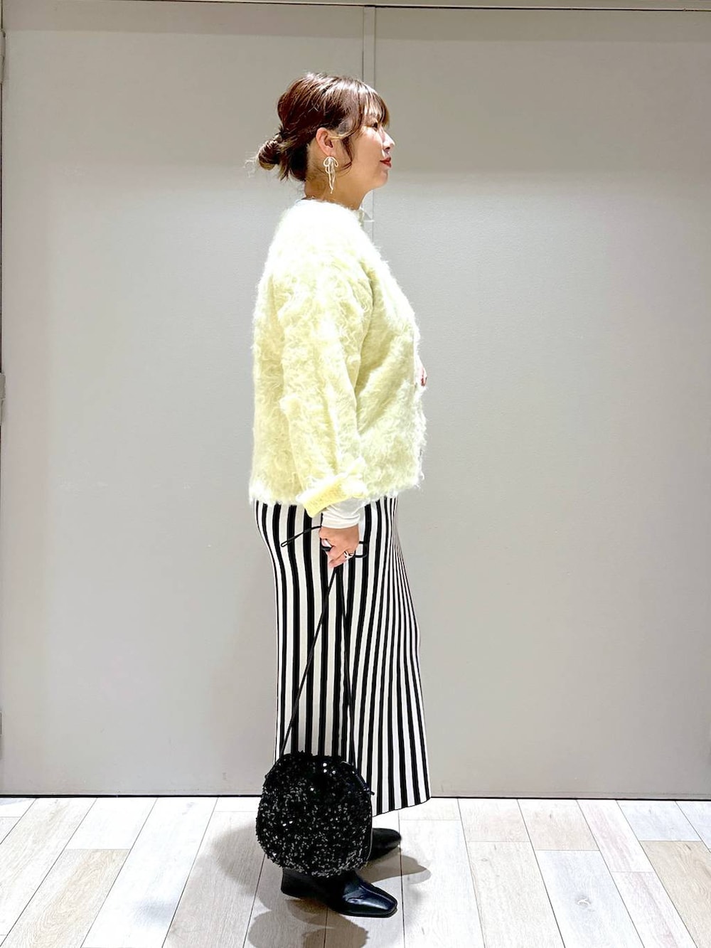 ブラック系のショルダーバッグ、ブラック系のスカート、グリーン系のカーディガン/ボレロを着用したレディースの秋コーディネートの2枚目の写真