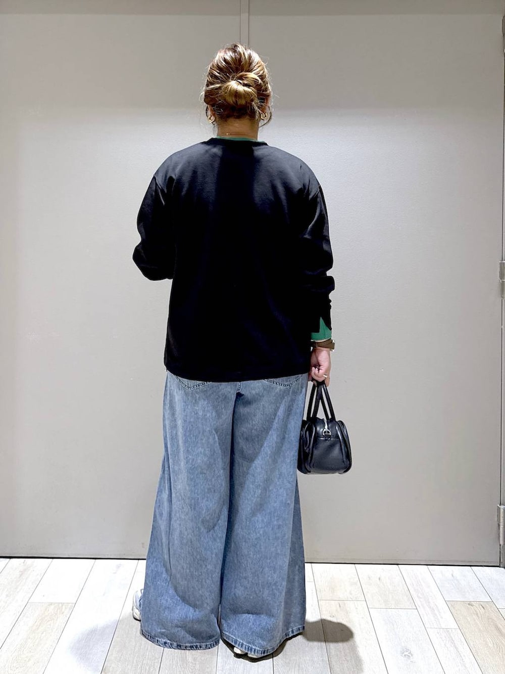 ブラック系のショルダーバッグ、ブラック系のTシャツ/カットソー、ブルー系のデニムパンツを着用したレディースの秋コーディネートの3枚目の写真