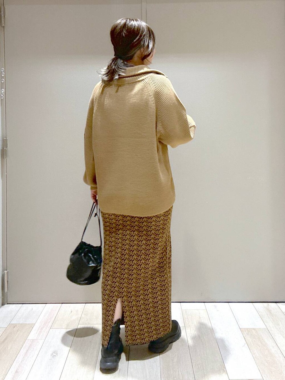 ブラウン系のスカート、ブラウン系のニット/セーター、ブラック系のブーツを着用したレディースの冬コーディネートの3枚目の写真