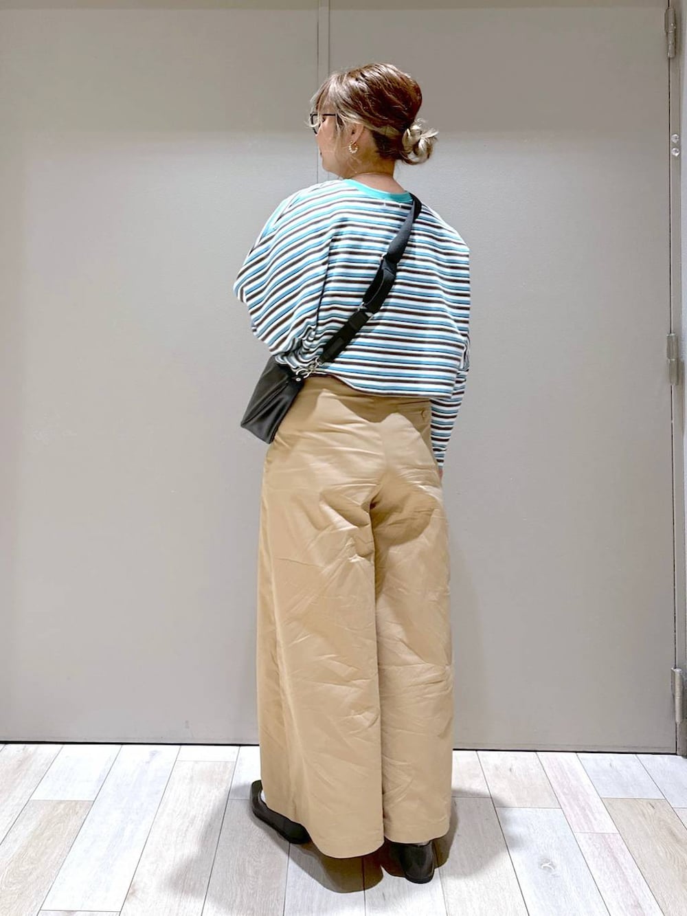 ブラック系のショルダーバッグ、ブラック系のパンプス、ベージュ系のチノパンツを着用したレディースの春コーディネートの3枚目の写真