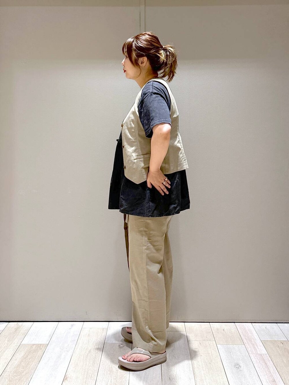 ブラック系のショルダーバッグ、ブラウン系のベスト、ベージュ系のサンダルを着用したレディースの夏コーディネートの2枚目の写真