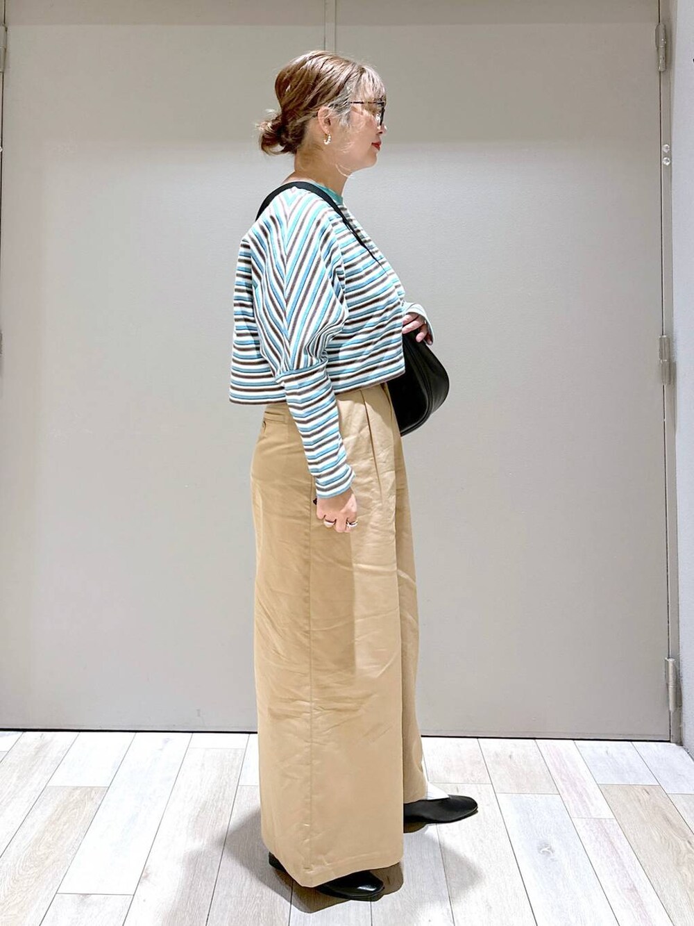 ブラック系のショルダーバッグ、ブラック系のパンプス、ベージュ系のチノパンツを着用したレディースの春コーディネートの2枚目の写真