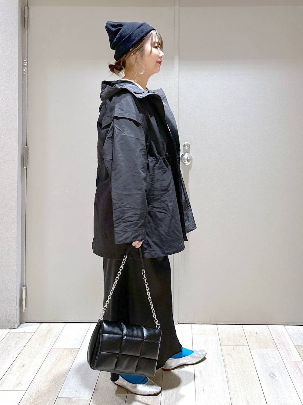 グレー系のチュニック、グレー系のパンプス、ブラック系のスカートを着用したレディースの春コーディネートの2枚目の写真