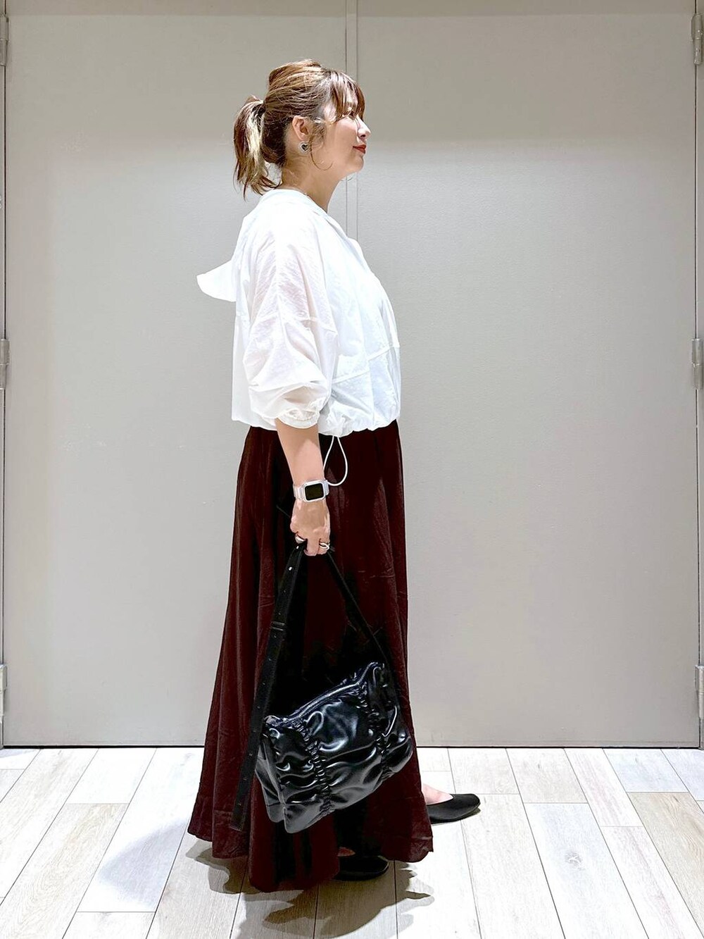 ブラック系のショルダーバッグ、ブラック系のパンプス、ブラウン系のスカートを着用したレディースの秋コーディネートの2枚目の写真