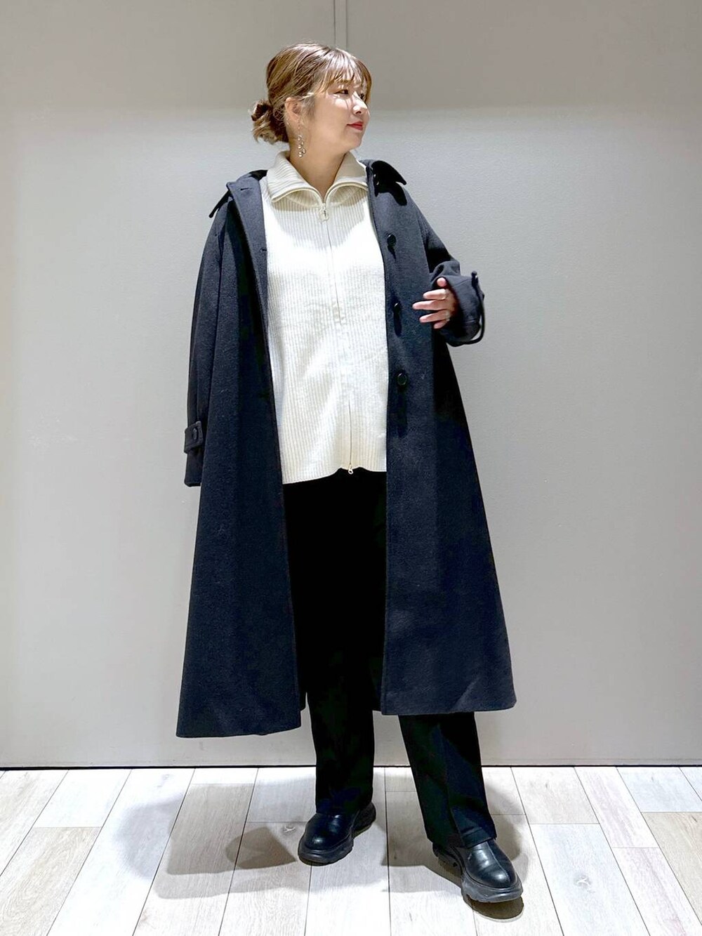 ブラック系のその他パンツ、グレー系のステンカラーコート、ホワイト系のニット/セーターを着用したレディースの冬コーディネートの2枚目の写真