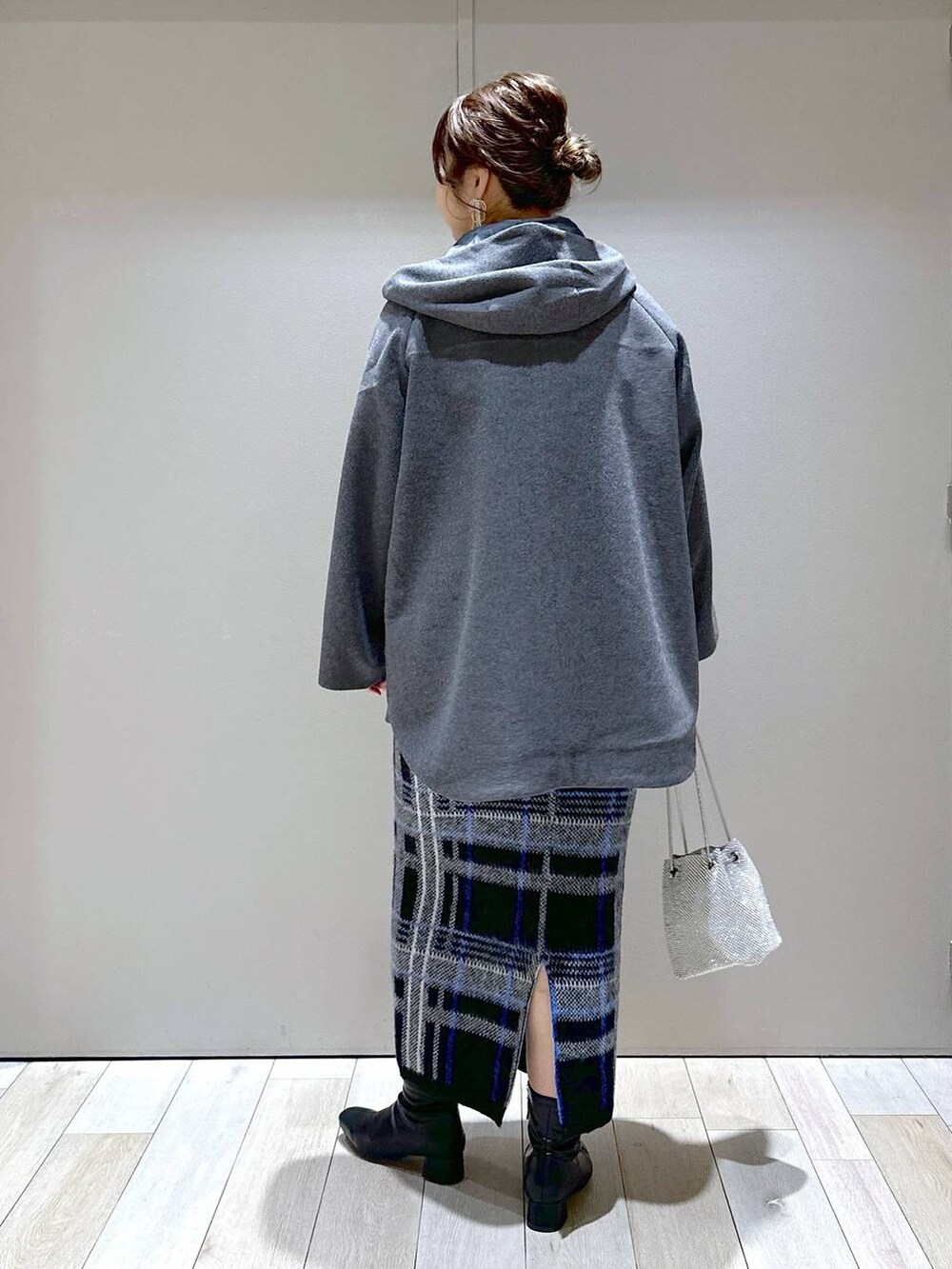 シルバー系のショルダーバッグ、グレー系のポンチョ、ブラック系のニット/セーターを着用したレディースの秋コーディネートの3枚目の写真