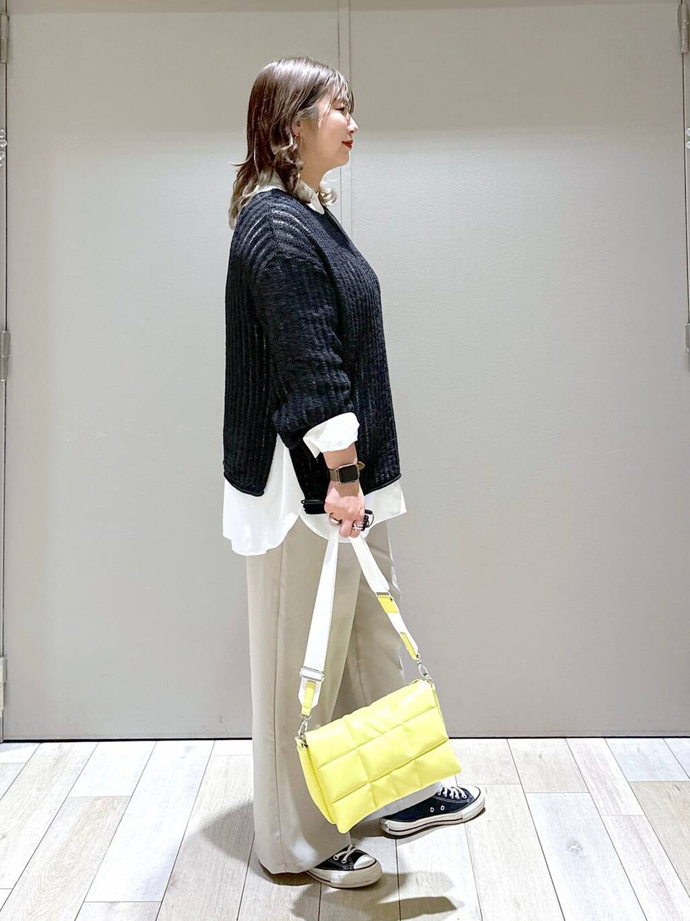 イエロー系のショルダーバッグ、ブラック系のTシャツ/カットソー、ベージュ系のスラックスを着用したレディースの春コーディネートの2枚目の写真