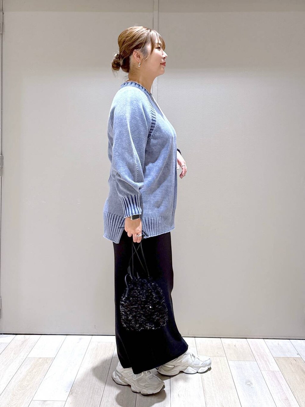 ブラック系のショルダーバッグ、ブラック系のスカート、ブルー系のニット/セーターを着用したレディースの冬コーディネートの2枚目の写真