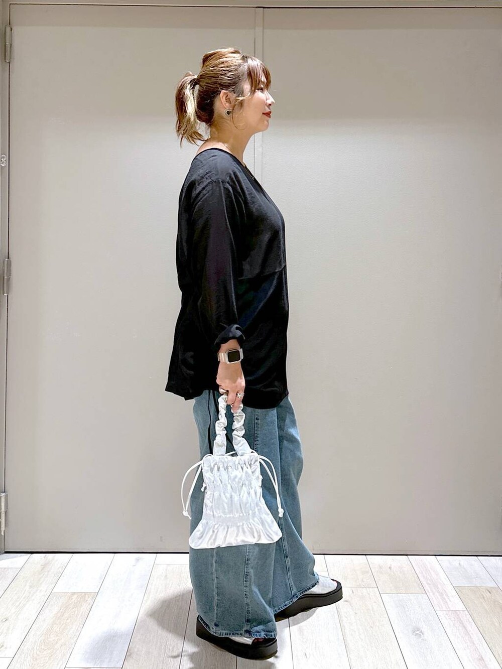 シルバー系のショルダーバッグ、ブルー系のデニムパンツ、シルバー系のサンダルを着用したレディースの秋コーディネートの2枚目の写真