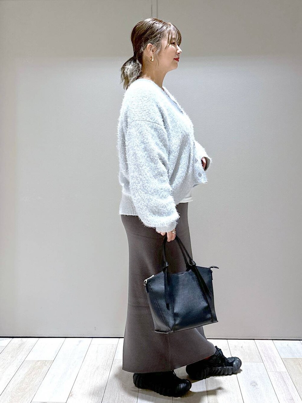 グレー系のスカート、ホワイト系のTシャツ/カットソー、ブラック系のショルダーバッグを着用したレディースの秋コーディネートの2枚目の写真