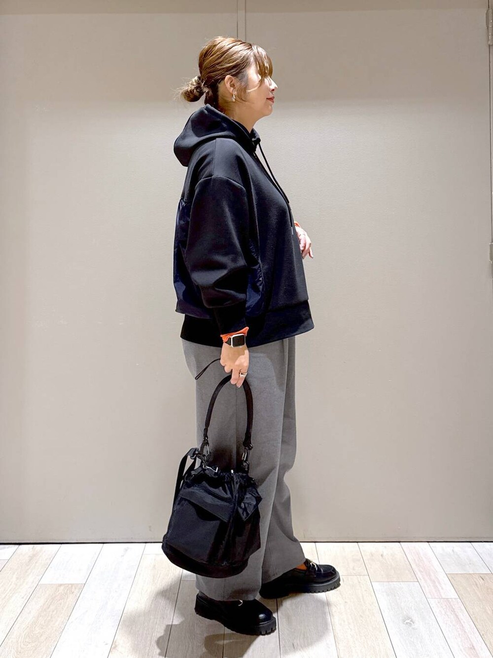 ブラック系のショルダーバッグ、ブラック系のパーカー、オレンジ系のTシャツ/カットソーを着用したレディースの冬コーディネートの2枚目の写真