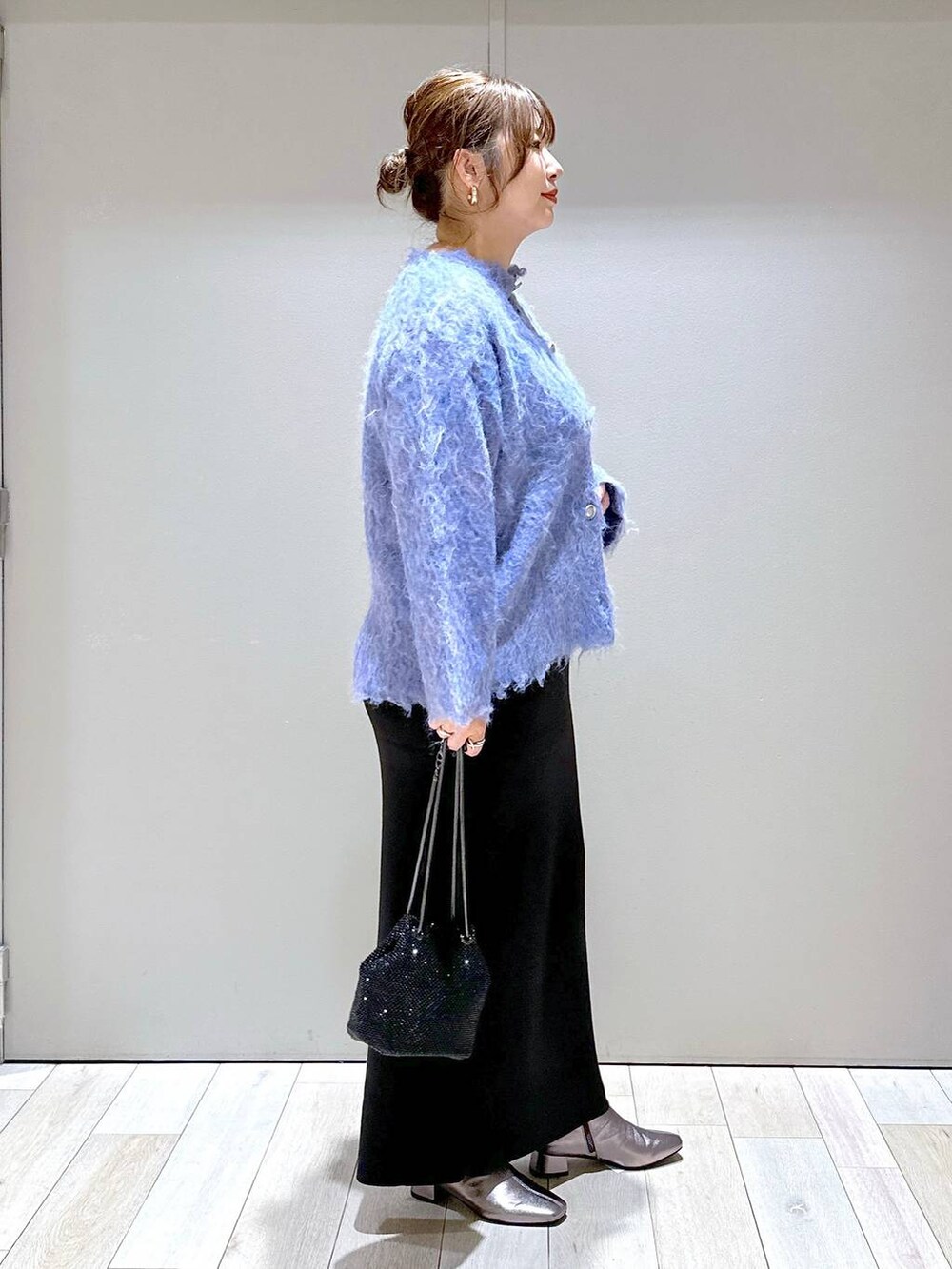 ブラック系のショルダーバッグ、ブラック系のスカート、ブルー系のカーディガン/ボレロを着用したレディースの秋コーディネートの2枚目の写真