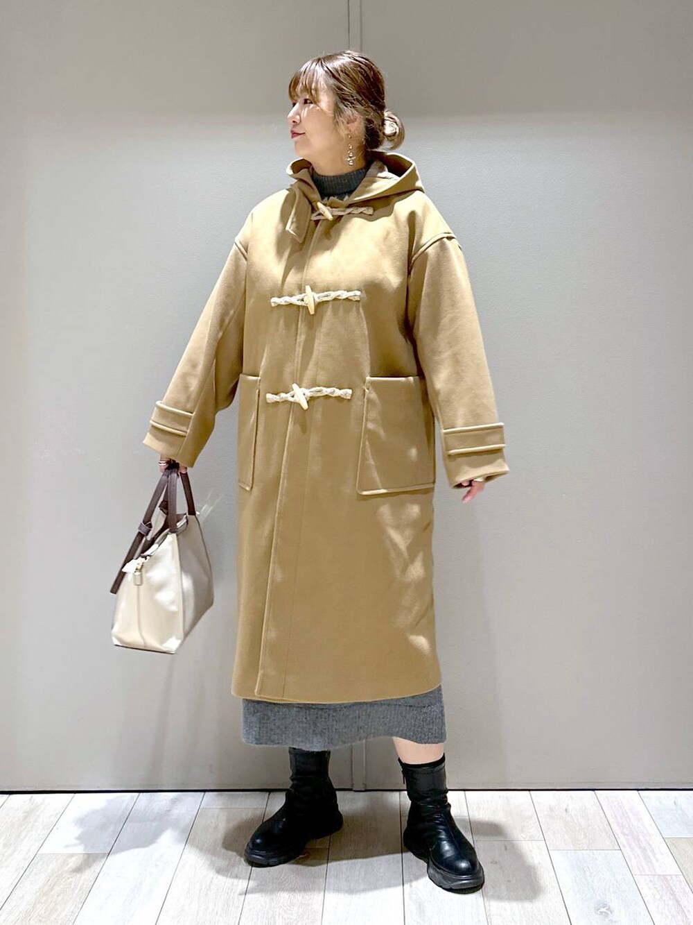 ベージュ系のショルダーバッグ、ブラウン系のダッフルコート、ブラック系のブーツを着用したレディースの冬コーディネートの4枚目の写真