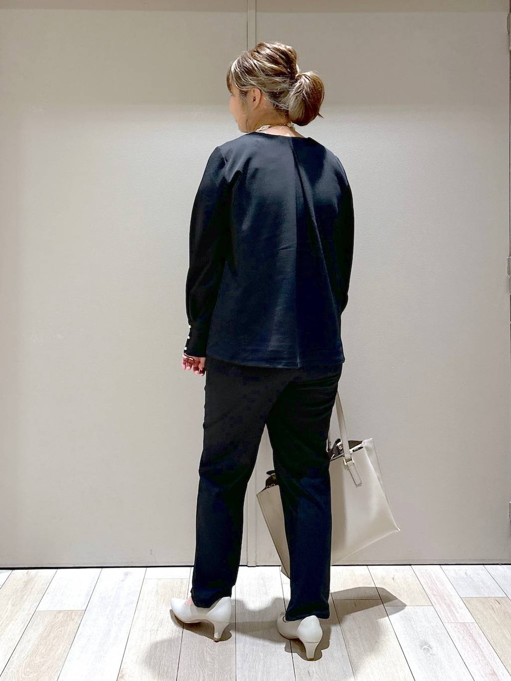 ブラック系のスラックス、ベージュ系のトートバッグ、ベージュ系のパンプスを着用したレディースの冬コーディネートの3枚目の写真