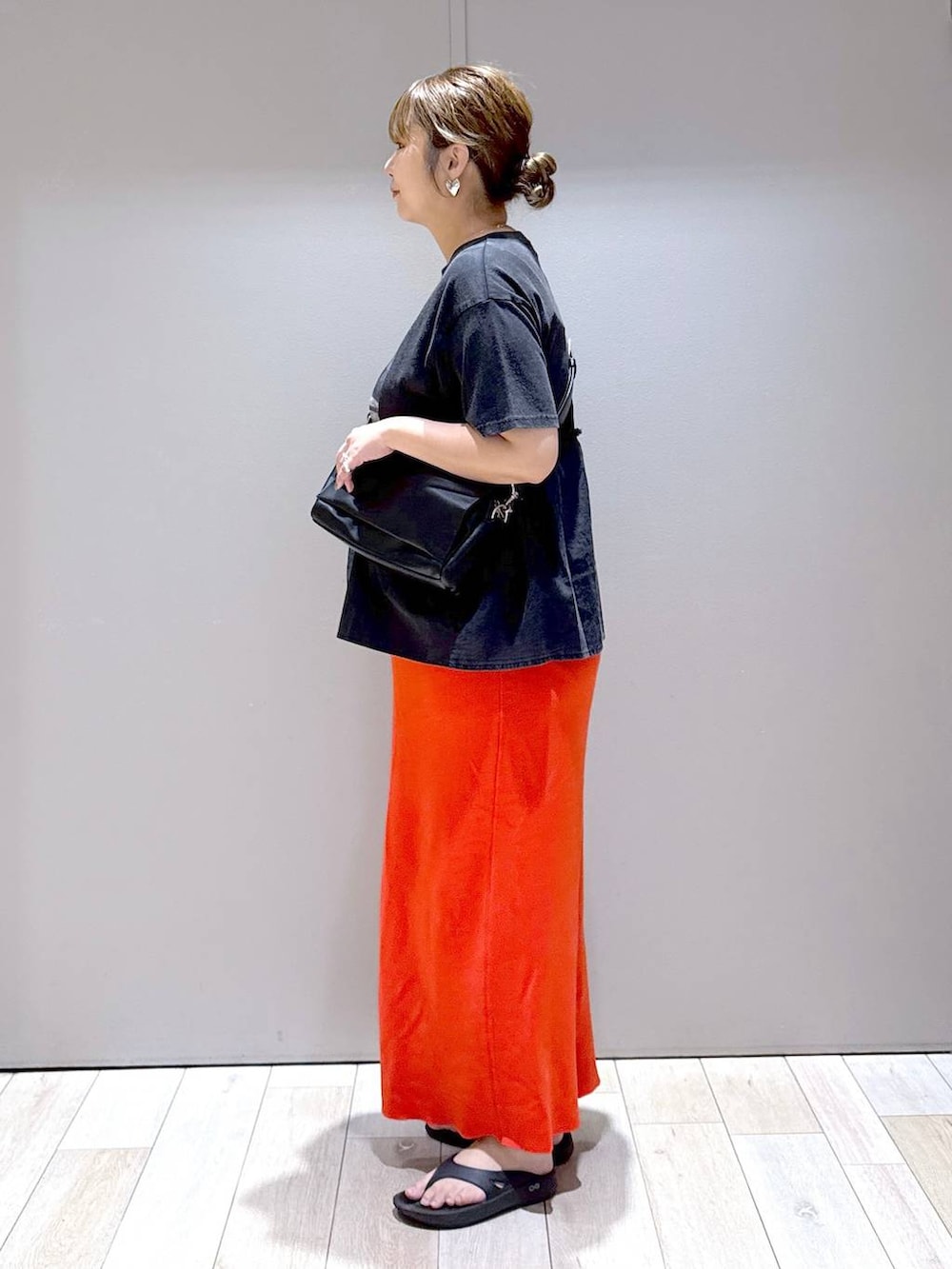 オレンジ系のスカート、ブラック系のTシャツ/カットソー、ブラック系のショルダーバッグを着用したレディースの夏コーディネートの4枚目の写真