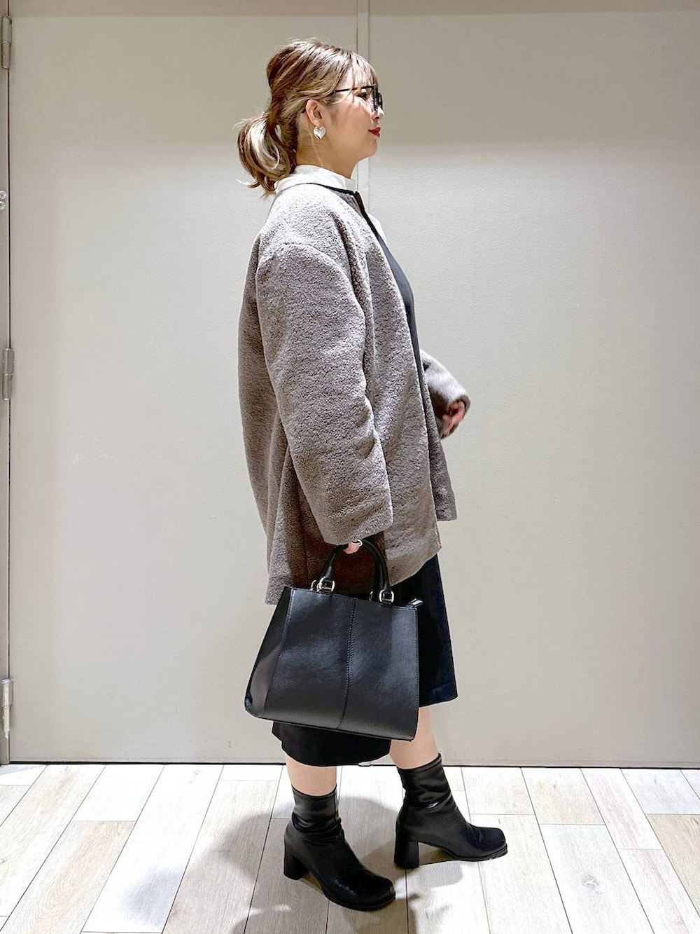 ブラウン系のノーカラーコート、ブラック系のブーツ、ホワイト系のシャツ/ブラウスを着用したレディースの冬コーディネートの3枚目の写真