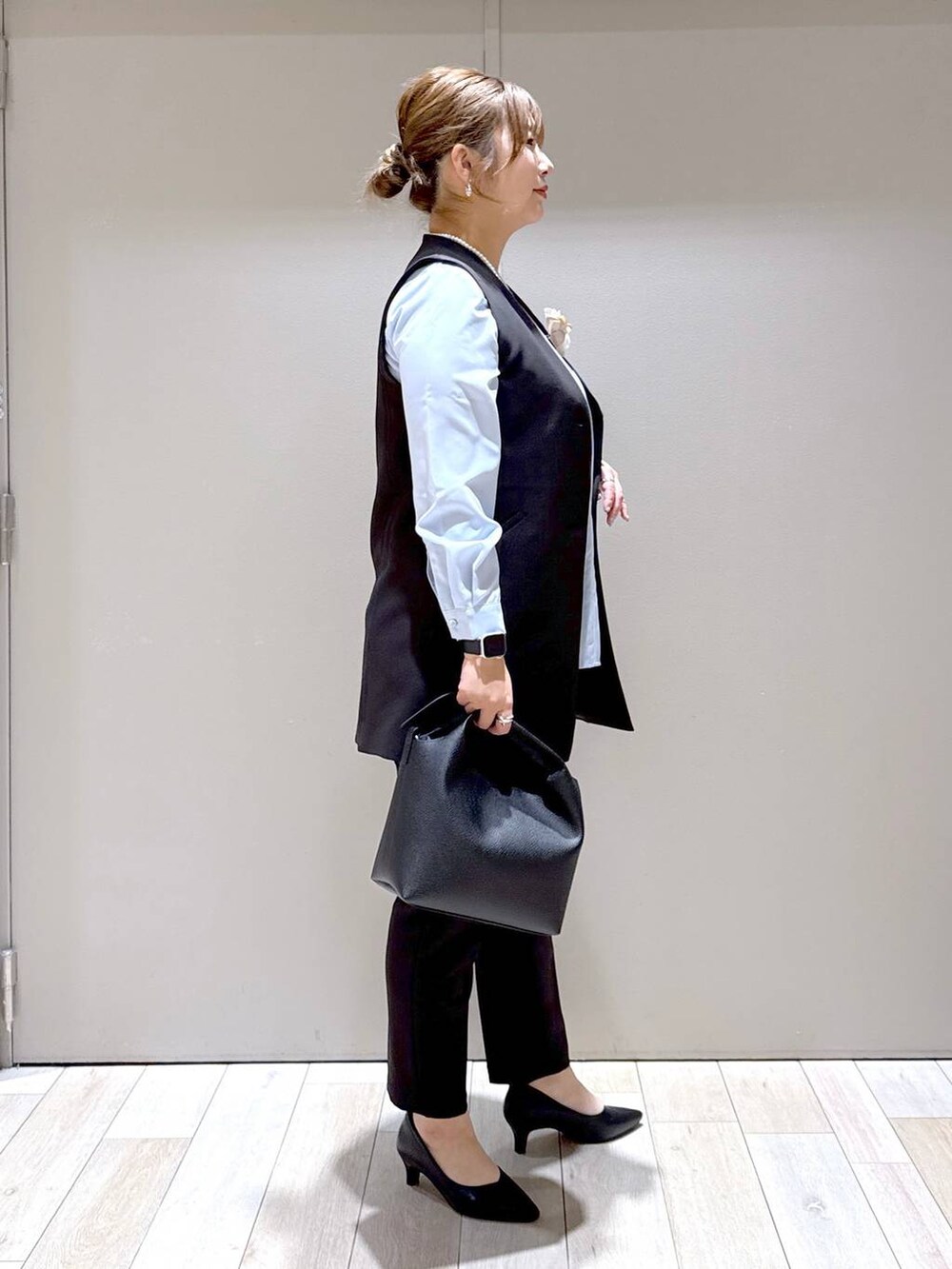 ブラック系のスーツパンツ、ブラック系のスーツベスト、ブルー系のシャツ/ブラウスを着用したレディースの冬コーディネートの2枚目の写真