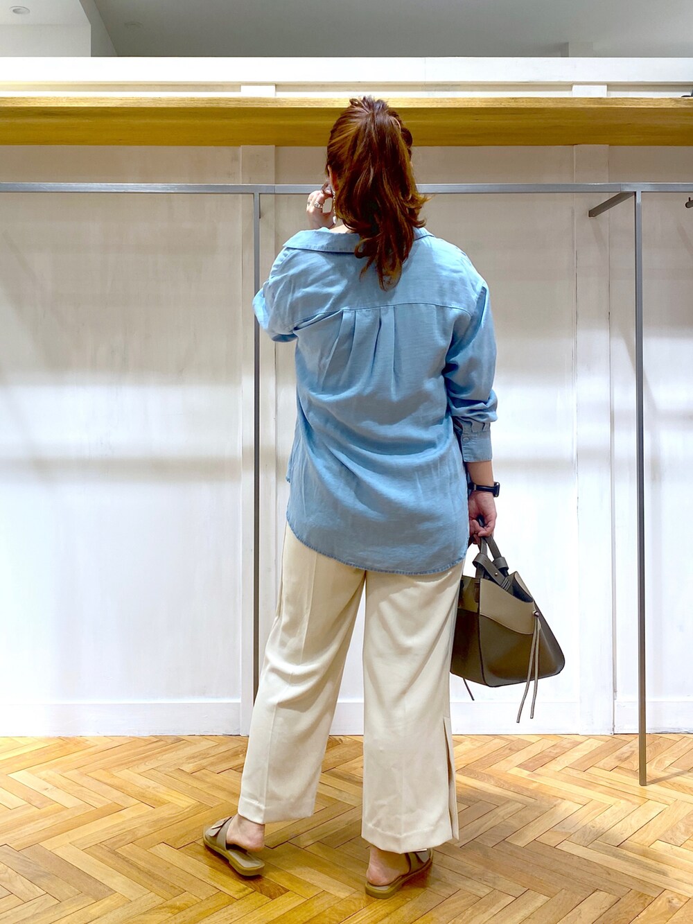 ブルー系のシャツ/ブラウス、ブラック系のニット/セーター、ホワイト系のスラックスを着用したレディースの夏コーディネートの3枚目の写真