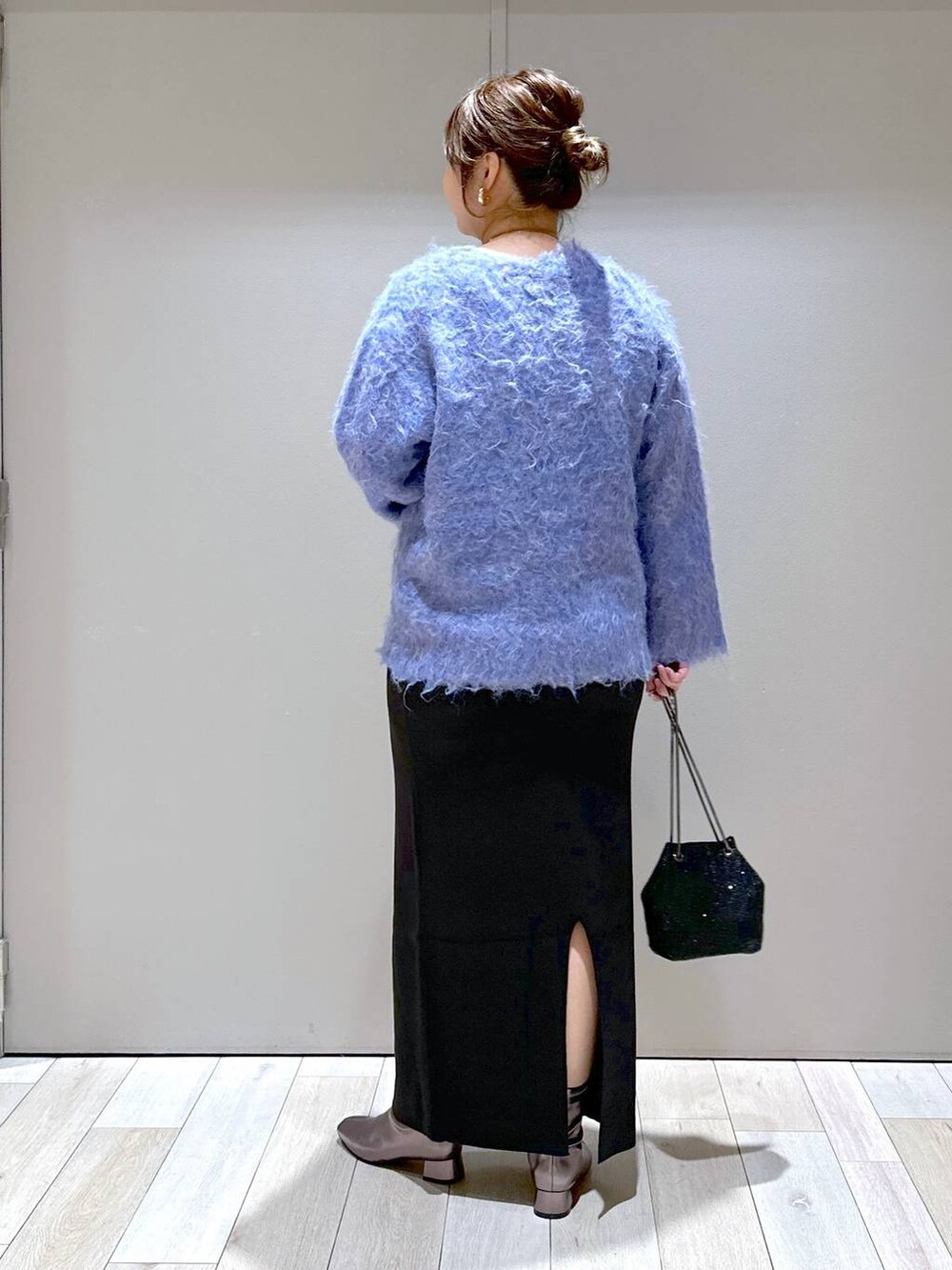 ブラック系のショルダーバッグ、ブラック系のスカート、ブルー系のカーディガン/ボレロを着用したレディースの秋コーディネートの3枚目の写真