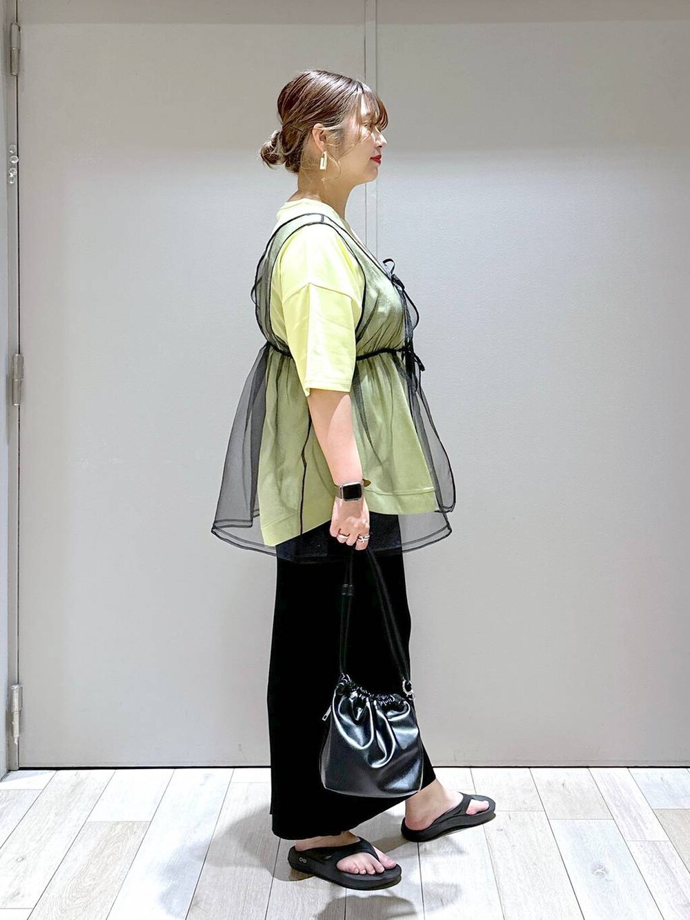 ブラック系のショルダーバッグ、ブラック系のベスト、ブラック系のサンダルを着用したレディースの春コーディネートの2枚目の写真